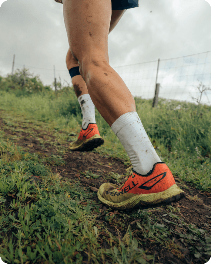 A person running through the a field wearing Merrell shoes.